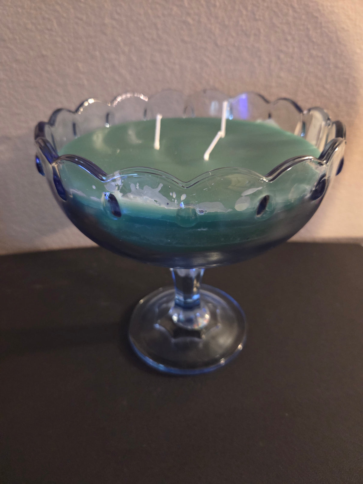 Mint sage soy wax candle with green wax in a scalloped glass pedestal bowl.